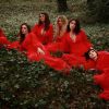 The Mediaeval Baebes dressed in red, sat in a forest