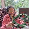 A lady making a Christmas wreath in a cosy home environment