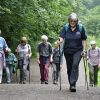 Six over 50s are following a Nordic walking leader up a hill