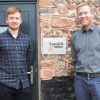 Two men in front of sign