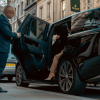 Security guard holding car door open for woman