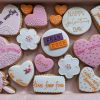 Purple, orange and white heart shaped and flower shaped cookies with empowering messages iced  on