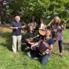 Six musicians playing instruments under a tree