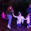 Two adults and two children run through trees in the dark