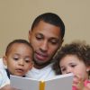 Photograph showing a man reading a book to two children