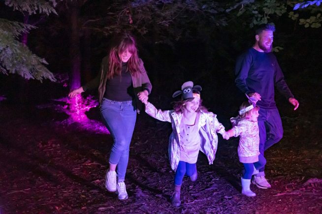 Two adults and two children run through trees in the dark