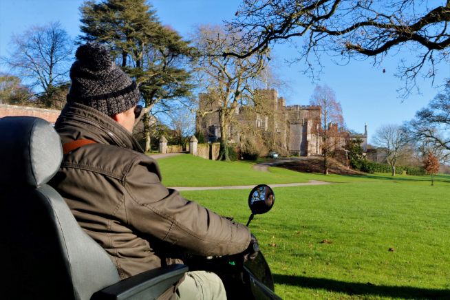 User of mobility scooter with Powderham Castle in the background