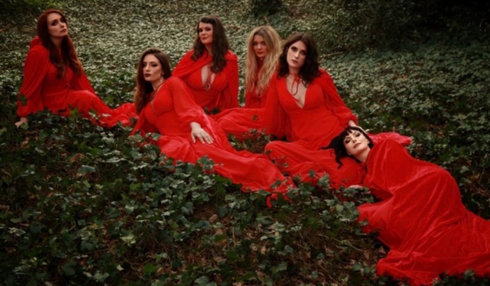 The Mediaeval Baebes dressed in red, sat in a forest