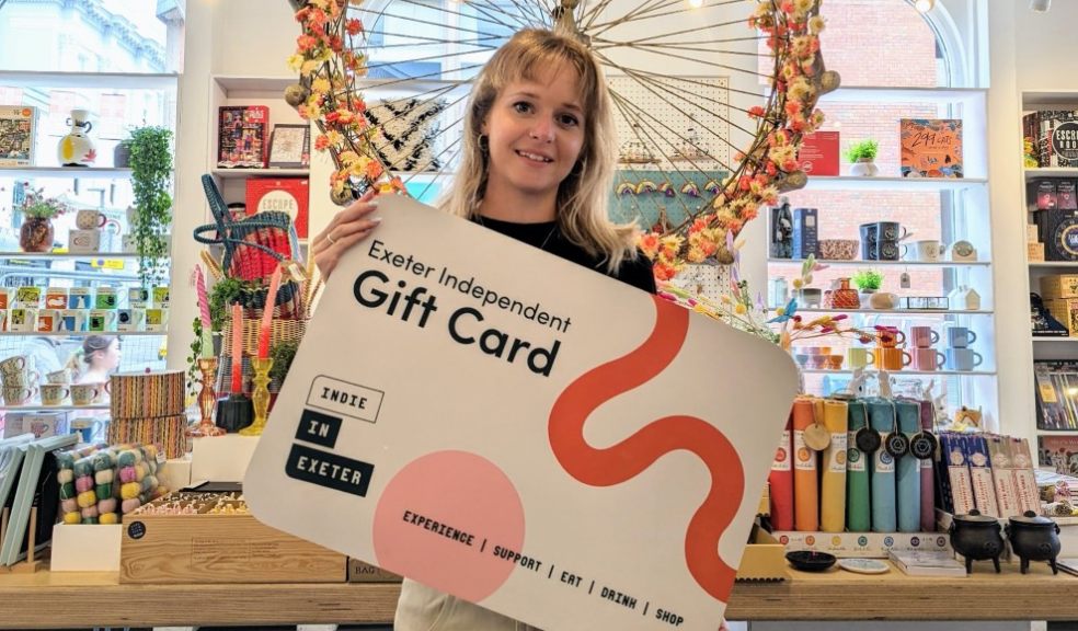 woman holding an Exeter Independent gift card in a shop