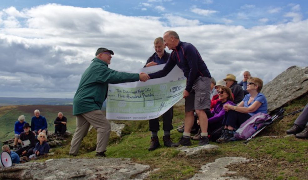 Devon Ramblers chairman Andrew Chadwick presents £500 cheque to Dartmoor Way project manager Michael Owen at the 50th anniversary celebration picnic on Hookney Tor (photo credit: Peter Walker)