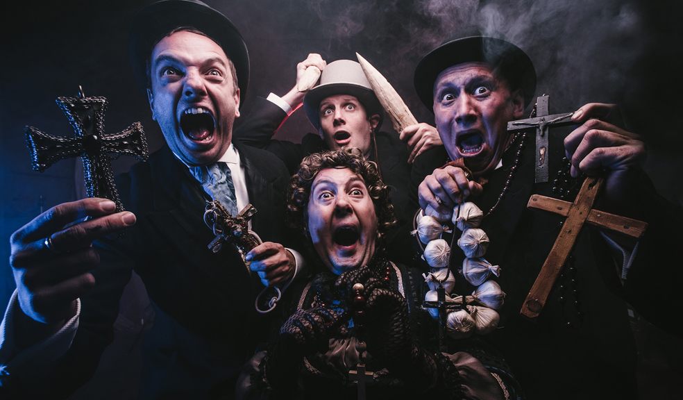 Le Navet Bete stand in a group holding garlic and crucifixes with a look of farcical fear on their faces. 