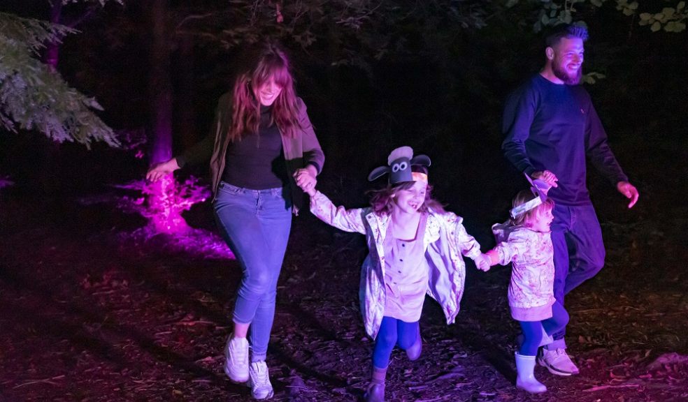 Two adults and two children run through trees in the dark