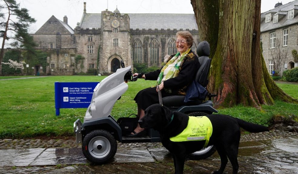 Friends of Dartington committee member Helen Robertson with Oscar on all terrain mobility scooter in Dartington Hall courtyard.