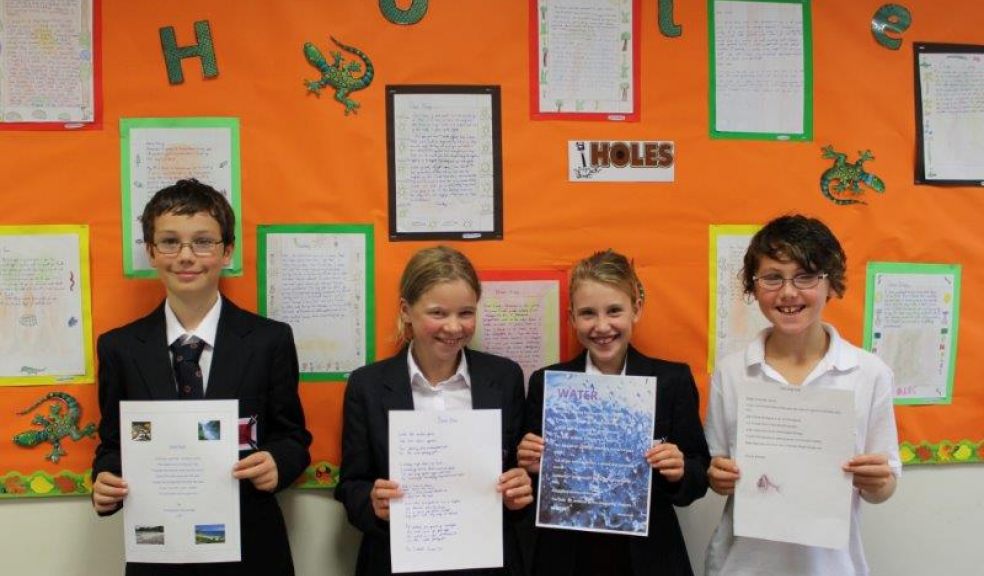 Exeter Junior School pupils holding their poems on water