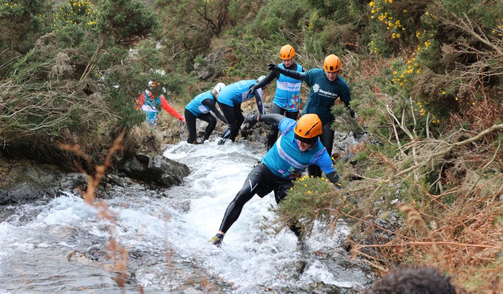 People in Hospiscare t-shirts scramble through a gorge