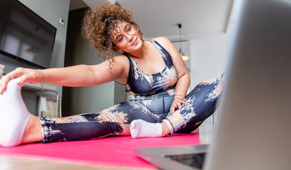 A woman exercising at home in front of a laptop computer