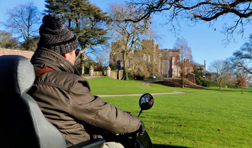 User of mobility scooter with Powderham Castle in the background