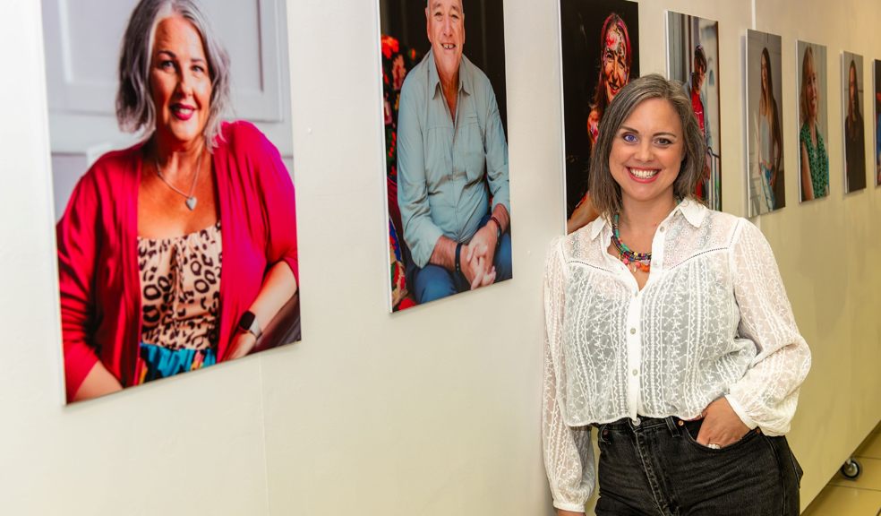 Woman standing in front of a series of portrait photographs depicting Everyday Bravery
