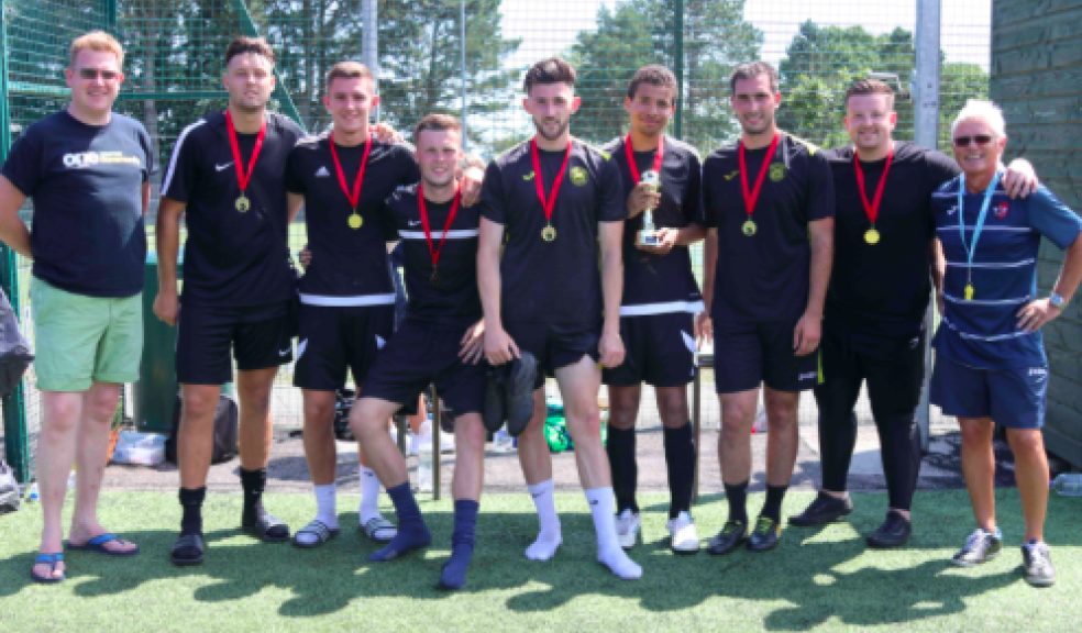 Marcel's Allstars, men's winners of the Exeter City Supporters Trust’s One Game One Community Group community diversity football tournament, with Simon Kitchen from ECFC OGOC group, left and Kevin Hack, right, from ECFC.