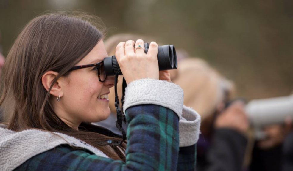 Woman smiling whilst looking at birds through her binoculars by Ben Andrew (rspb-images.com)