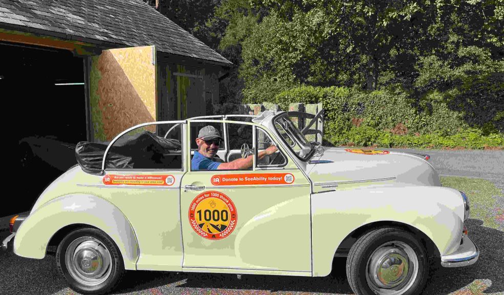 A man sits in the driving seat of a white vintage car