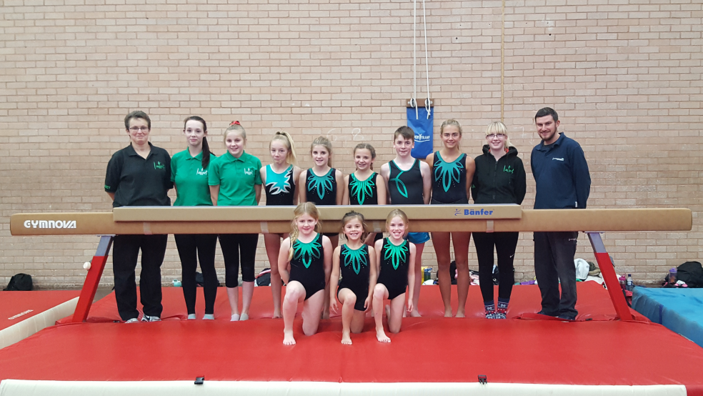 Tom Halfyard (left) with his daughter Ella (front right) along with the team and their coach, standing with the new beam.