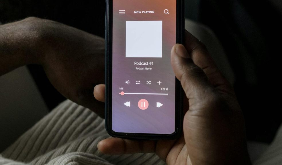man holding a smartphone in his hands listening to a podcast