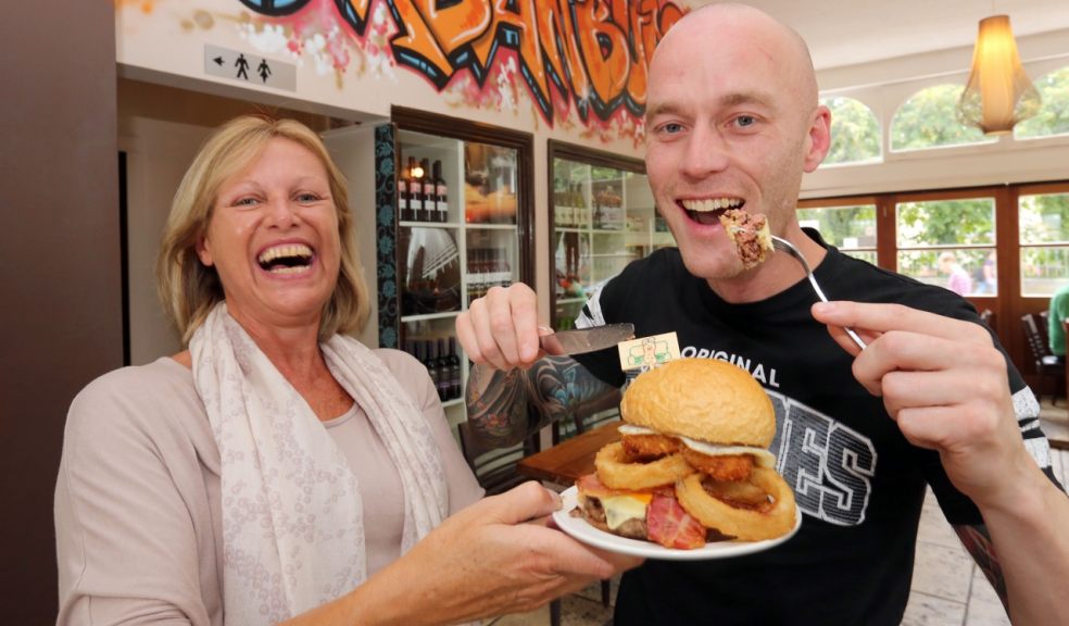 Shane Howe tucks in to a breakfast burger at Urban Burger with owner Melissa Pearse.