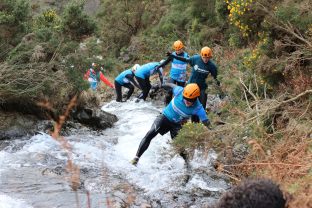 People in Hospiscare t-shirts scramble through a gorge