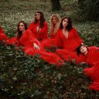 The Mediaeval Baebes dressed in red, sat in a forest