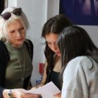 Queen Elizabeth's School GCSE Results Day Three people gather indoors, reviewing exam results; an older woman leans beside two young women.