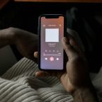 man holding a smartphone in his hands listening to a podcast