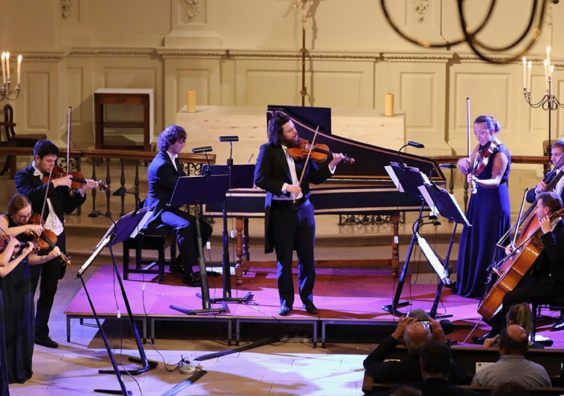 Orchestra playing separate instruments at concert
