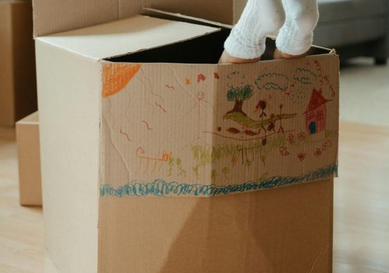 Moving boxes with child's scribble with feet hanging out