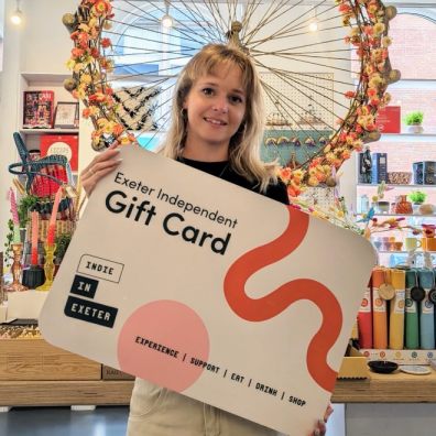 woman holding an Exeter Independent gift card in a shop