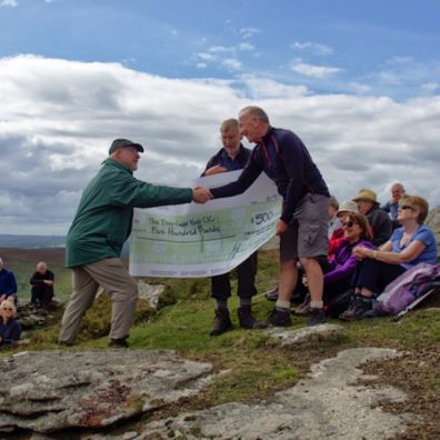 Devon Ramblers chairman Andrew Chadwick presents £500 cheque to Dartmoor Way project manager Michael Owen at the 50th anniversary celebration picnic on Hookney Tor (photo credit: Peter Walker)