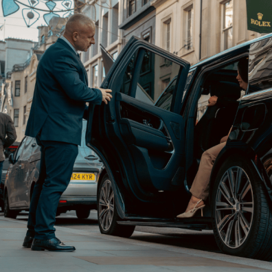 Security guard holding car door open for woman Security guard holding car door open for woman