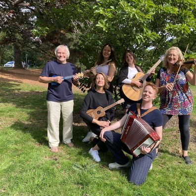Six musicians playing instruments under a tree