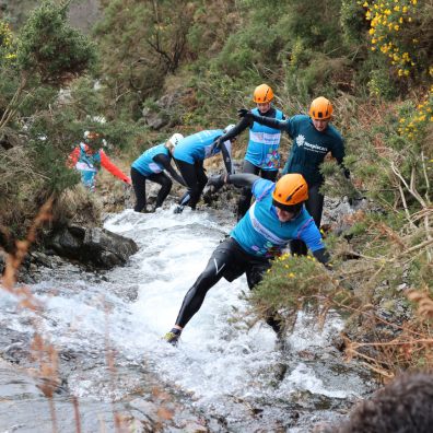 People in Hospiscare t-shirts scramble through a gorge