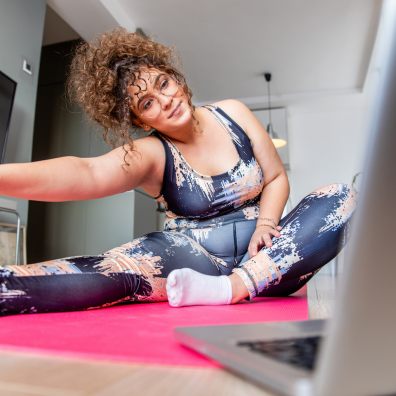A woman exercising at home in front of a laptop computer