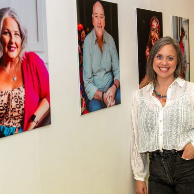 Woman standing in front of a series of portrait photographs depicting Everyday Bravery