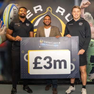 Celebrity Chef Michael Caines, with two Exeter Chiefs rugby players holding  a £3 million board 