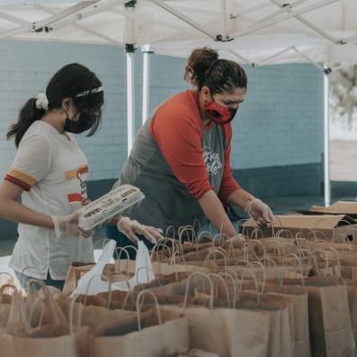 Two women in masks packing food bags